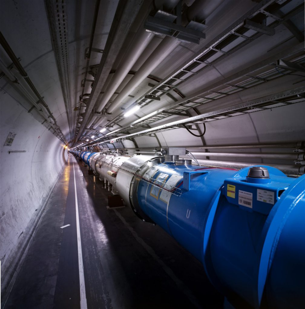 Underground concrete tunnel with a blue metal pipe running through its length
