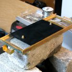 Colour photograph of a glass plate smoked with soot from a candle flame installed on top of the glass bed of the brass stage