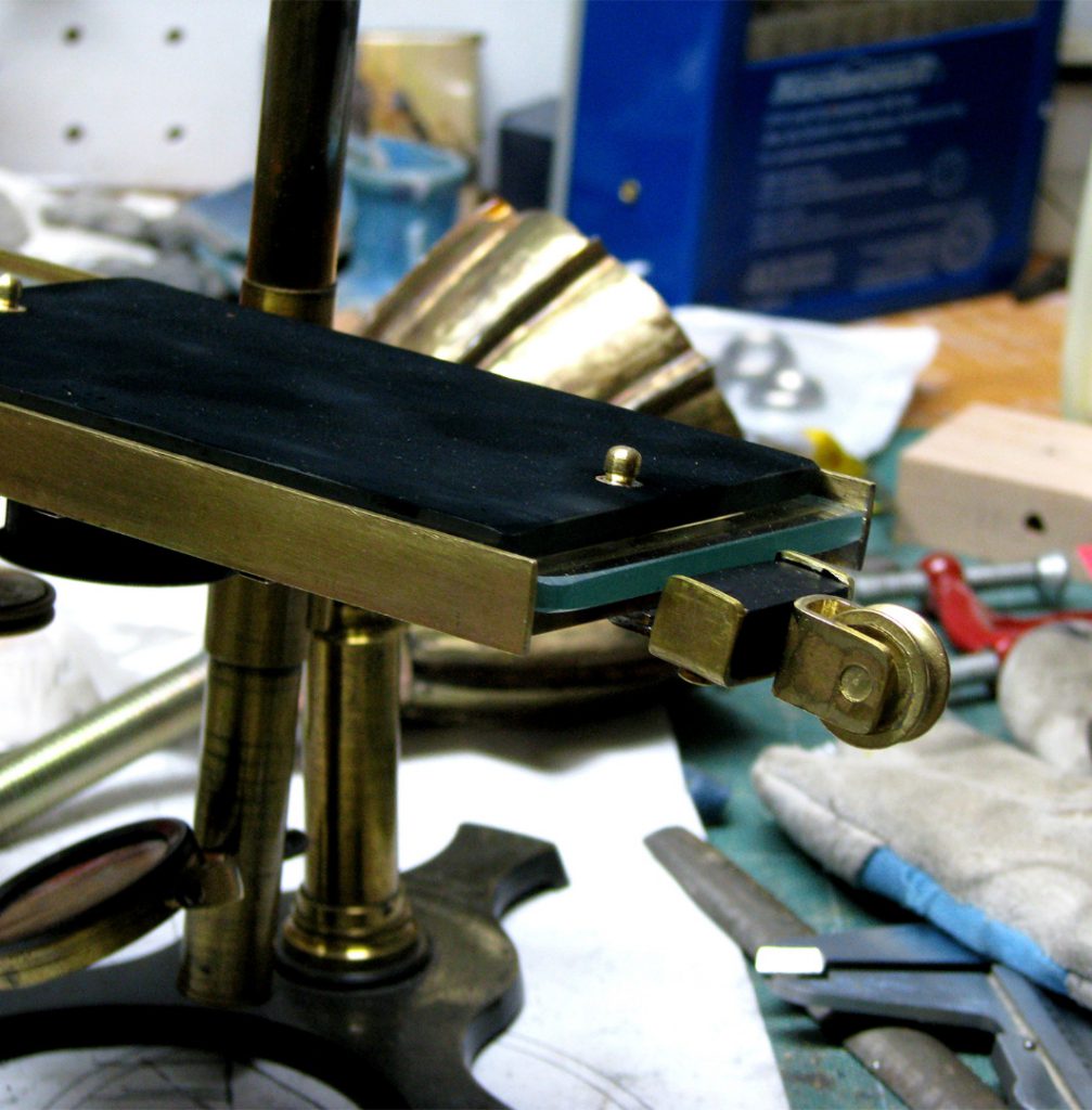 Colour photograph of a glass plate smoked with soot from a candle flame installed on top of the glass bed of the brass stage