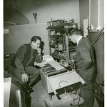 Black and white photograph of William Grey Walter and Ray Cooper at the BNI looking at an EEG