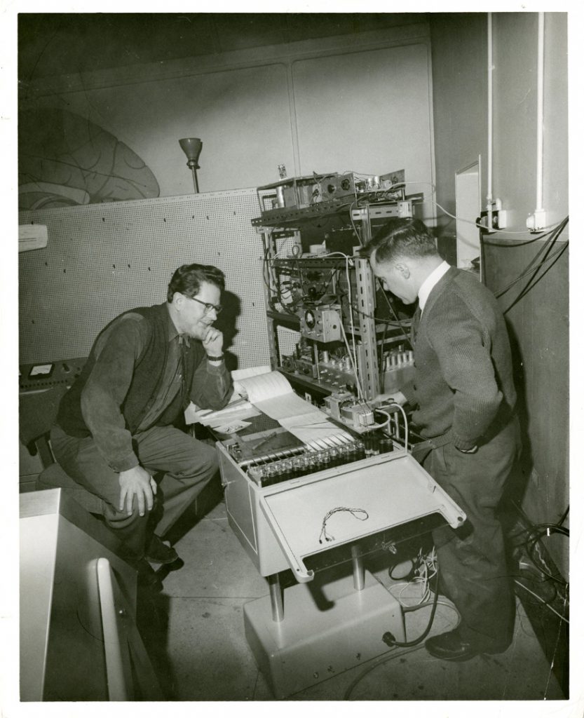 Black and white photograph of William Grey Walter and Ray Cooper at the BNI looking at an EEG