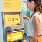 Colour photograph of a museum visitor interacting with a slot machine display case