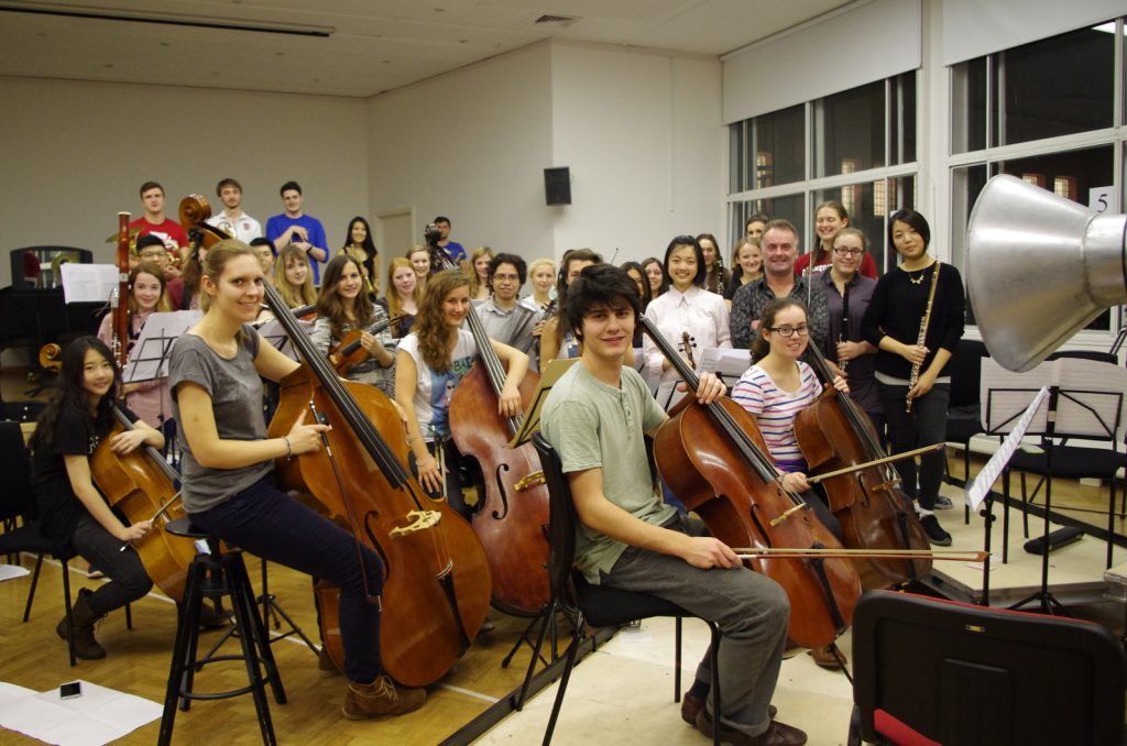 Colour photograph of the RCM chamber orchestra and conductor looking to camera