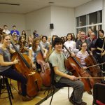 Colour photograph of the RCM chamber orchestra and conductor looking to camera