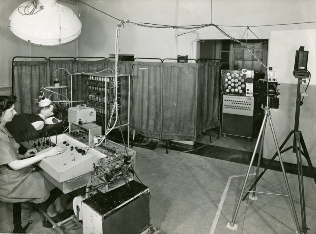 Black and white photograph of Janet Shipton with a six channel EEG in 1955