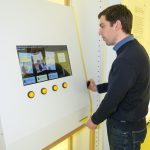Colour photograph of a museum visitor viewing a digital display