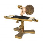 Colour photograph of a 3d printed inner ear attached to a brass mouthpiece and a glass etching plate