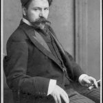 A black and white photographic portrait of Arthur Nikisch seated wearing a waistcoat and jacket and holding a cigarette