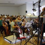 Colour photograph of the cellos and basses part of the royal college of music chamber orchestra recording music to wax discs