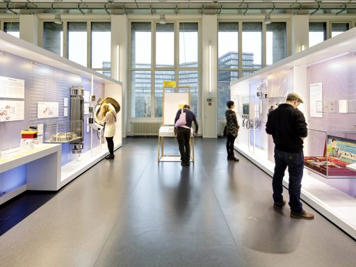 Colour photograph of a bright exhibition space with display objects and visitors