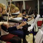 Colour photograph of members of RCM playing Stroh instruments
