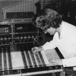 Black and white photograph of Daphne Oram leaning over the Oramics Machine and drawing black lines on one of the acetate strips