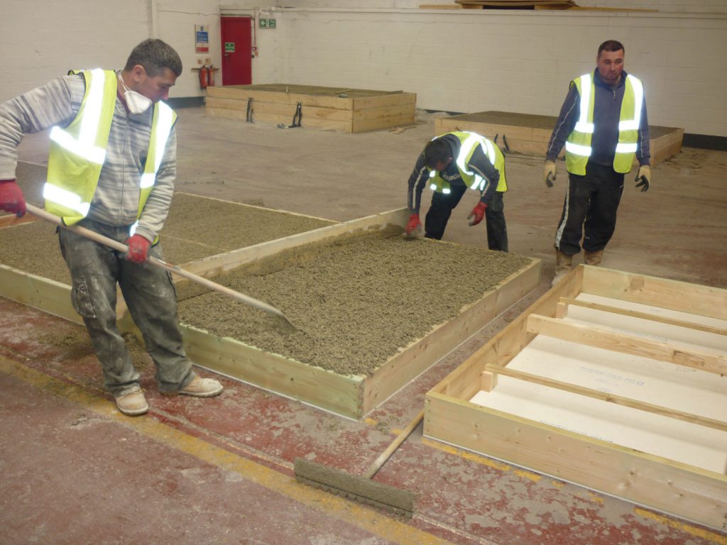 Colour photograph of workers precasting hempcrete panels for use in the storage building