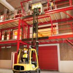 Colour photograph showing transportation of objects to upper storeys of the structure using a forklift truck