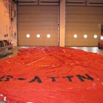 Colour photograph of a large deflated hot air balloon canvas spread on the floor of a warehouse
