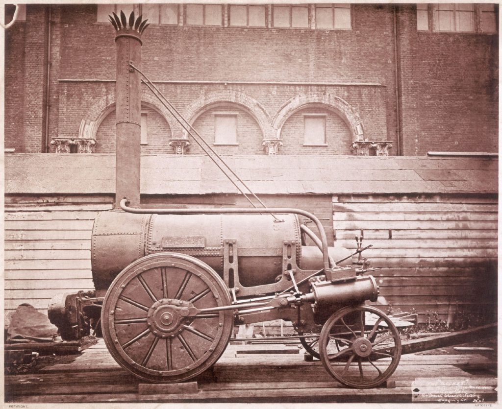 Sepia photograph of the Rocket steam powered rail engine outside the Patent Office Museum
