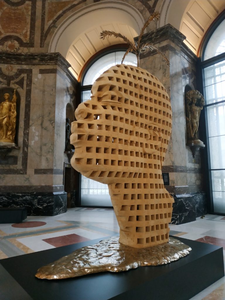 Colour photograph of a wood and bronze sculpture of a stylised human head
