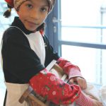 Colour photograph of a young girl demonstrating the use of a clothes washing board