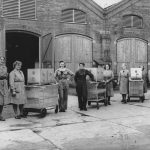 Black and white photograph of a number of women standing with their tea trollies