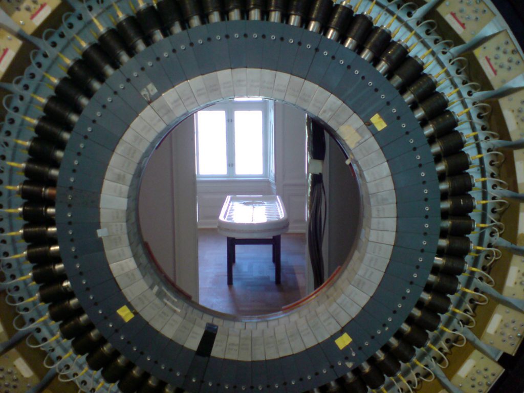Colour photograph of a medical exhibition showing an MRI scanner and an operating table
