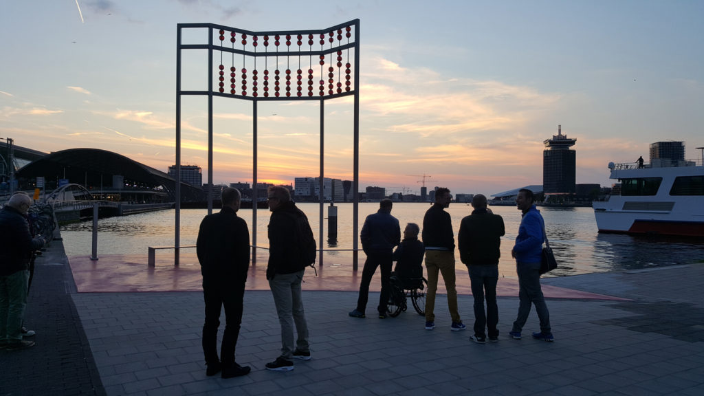 Colour photograph of evening visitors to an AIDS monument in Amsterdam