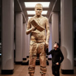 Colour photograph of the Self Conscious Gene sculpture situated on gallery with artist Marc Quinn