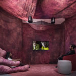 Colour photograph of attendees viewing a video in the Oreet Ashery exhibition