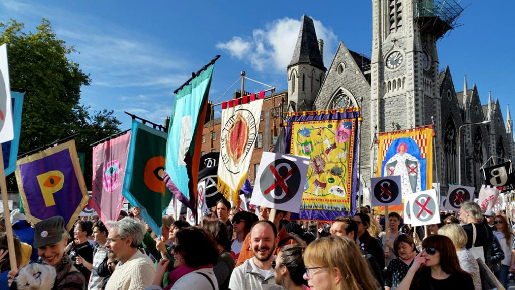 A group of protesters hold colourful banners in support of repealing irish abortion law