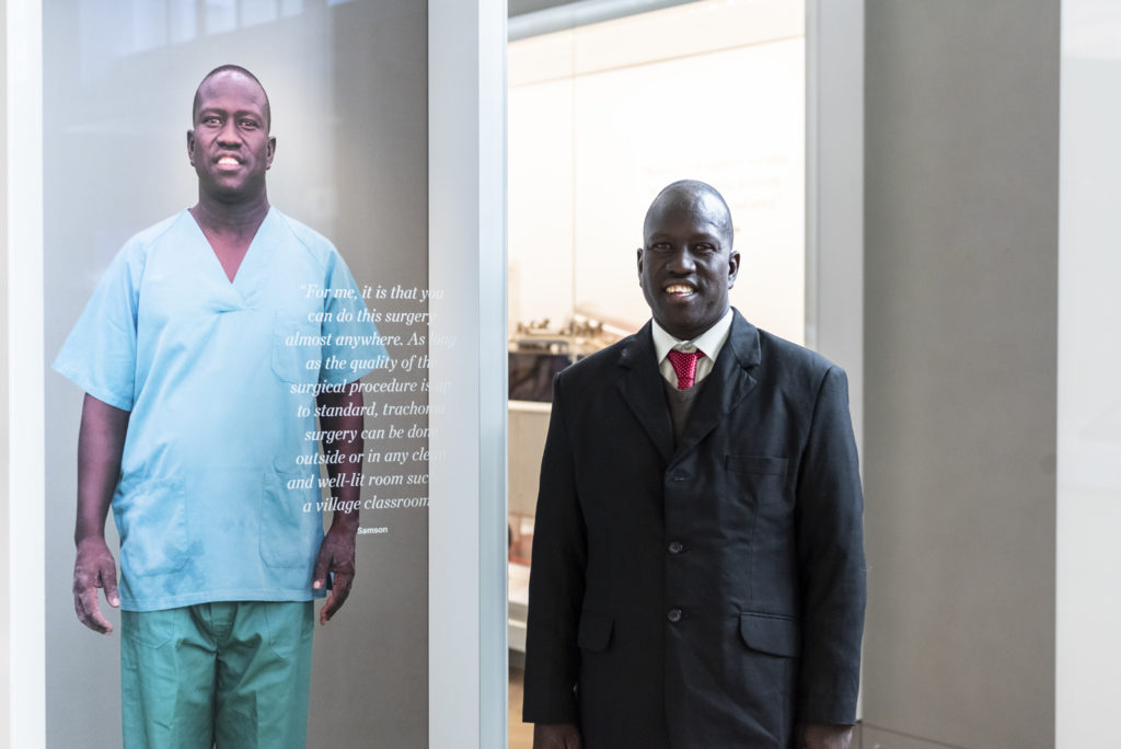 Colour photograph of a man standing alongside his on gallery portrait