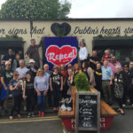 A group of people hold a hand knitted Repeal protest banner outside a Dublin pub