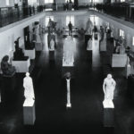 Black and white photograph of stone figure sculptures in a museum
