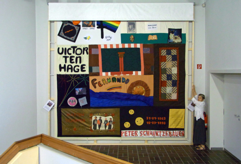 Colour photograph of a woman unveiling an AIDS memorial quilt