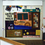 Colour photograph of a woman unveiling an AIDS memorial quilt