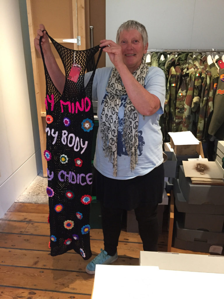 A woman holds up a dress stitched with the slogan My Mind My Body My Choice