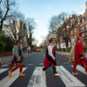Colour photograph of traditionally dressed native Americans on a zebra crossing