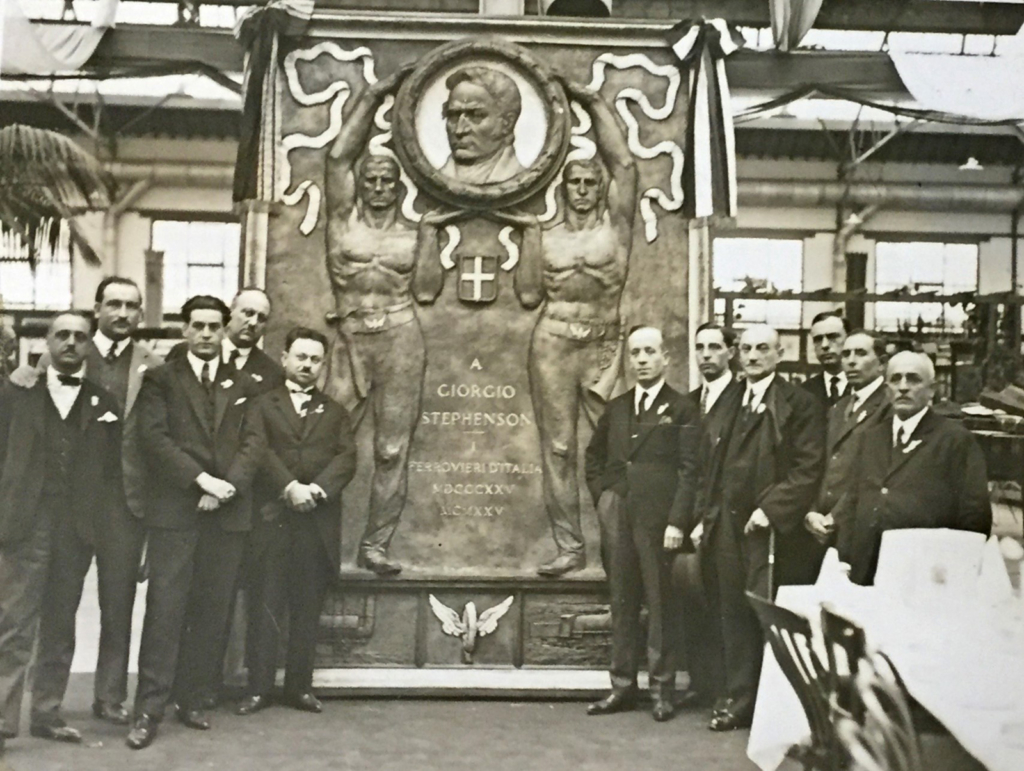 Black and white photograph of a delegation alongside their bronze plaque in honour of George Stephenson