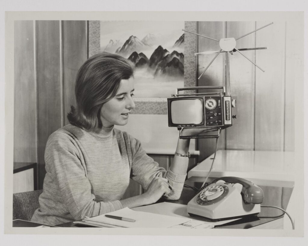 Black and white photograph of a woman holding a portable television