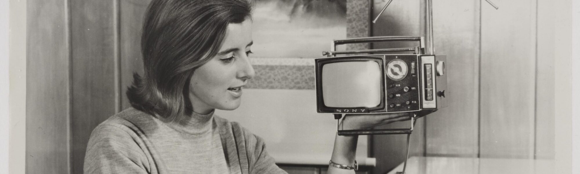 Black and white photograph of a woman holding a portable television
