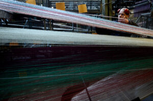 Photograph of a man preparing the warp threads on a Jacquard loom