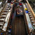 Photograph of a woman weaving glass fibre on a specialised loom