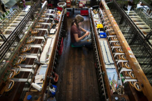 Photograph of a woman weaving glass fibre on a specialised loom