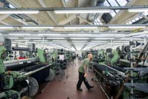 Photograph of a male worker in a worsted cloth weaving shed