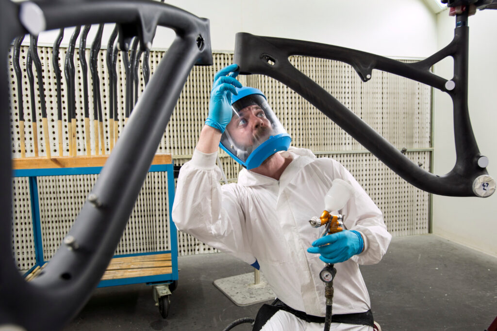 Photograph of a man working on bicycle frames made from woven carbon