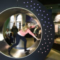 Colour photograph of girl inside an interactive spinning wheel display at the National Museum of Scotland