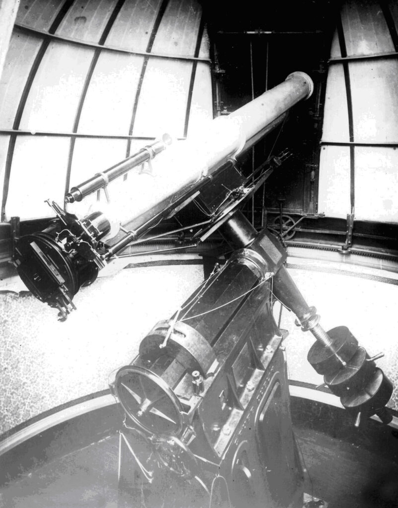 Monochrome photograph of an astrographic reflector installed within an observatory tower